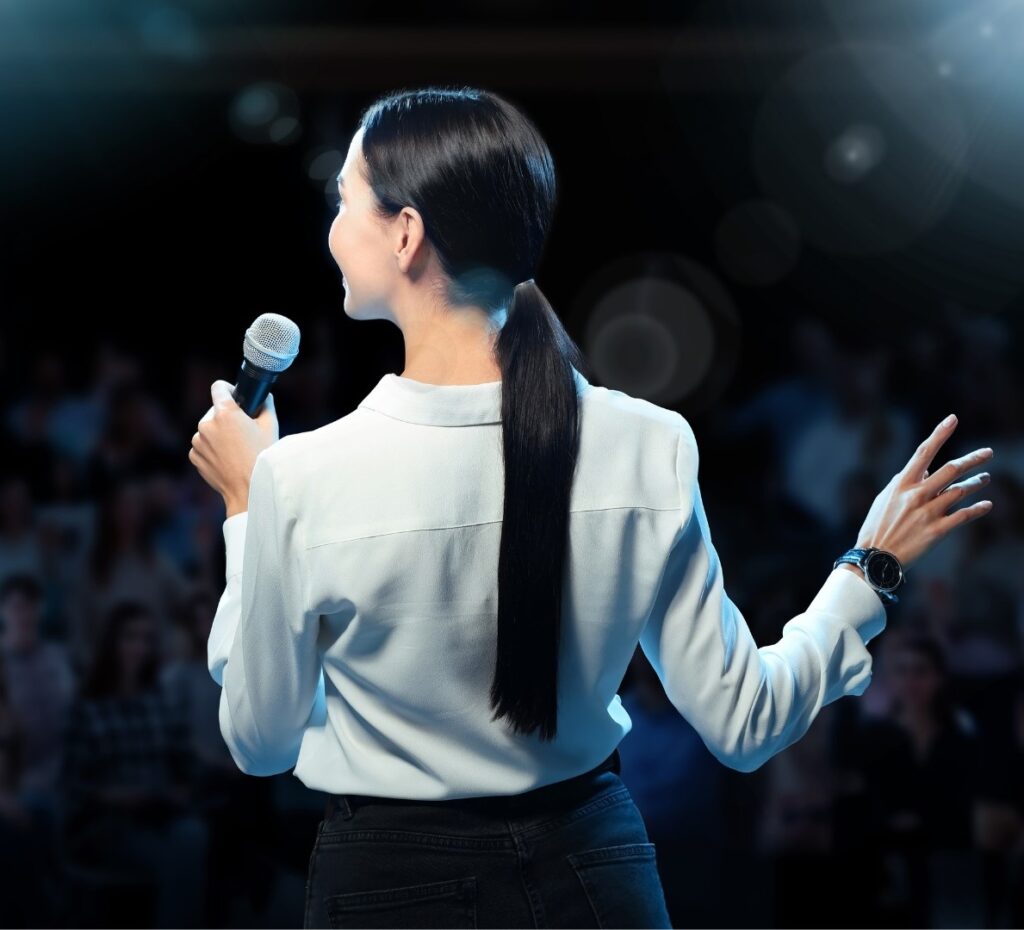 Female public speaker with a microphone in front of an audience